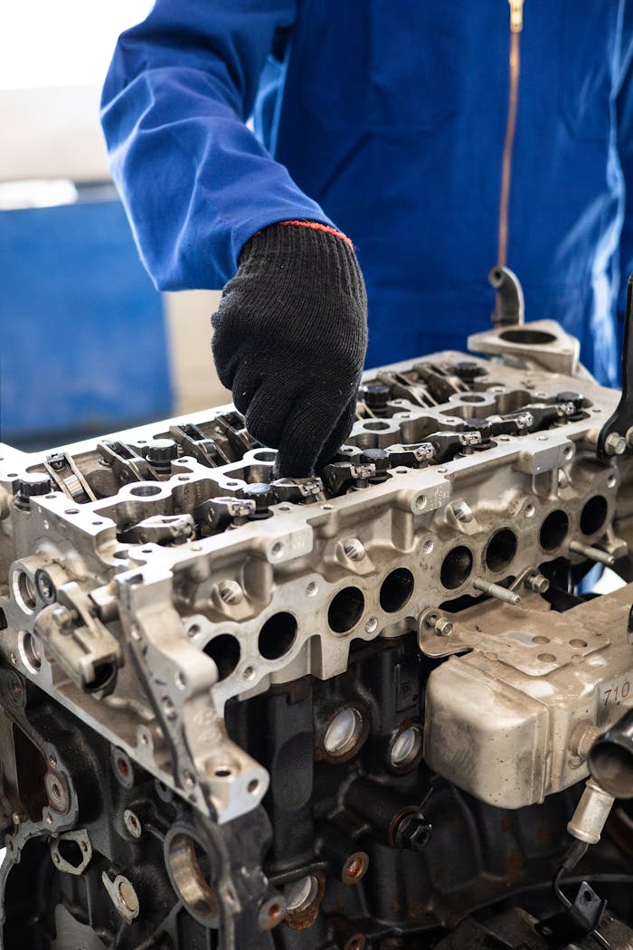 why-choose-us-02 Close-up of a mechanic in gloves working on a car engine cylinder head in a workshop setting.